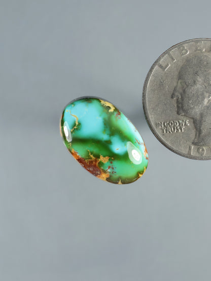 Oval turquoise cabochon gemstone, domed green with brown speckles and smooth polished finish