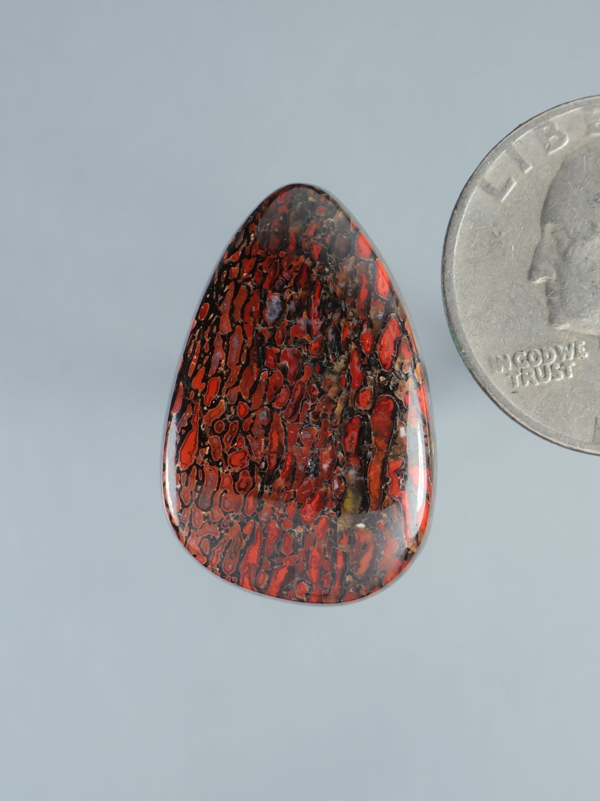 Red and black gembone cabochon gemstone, oval teardrop with polished surface