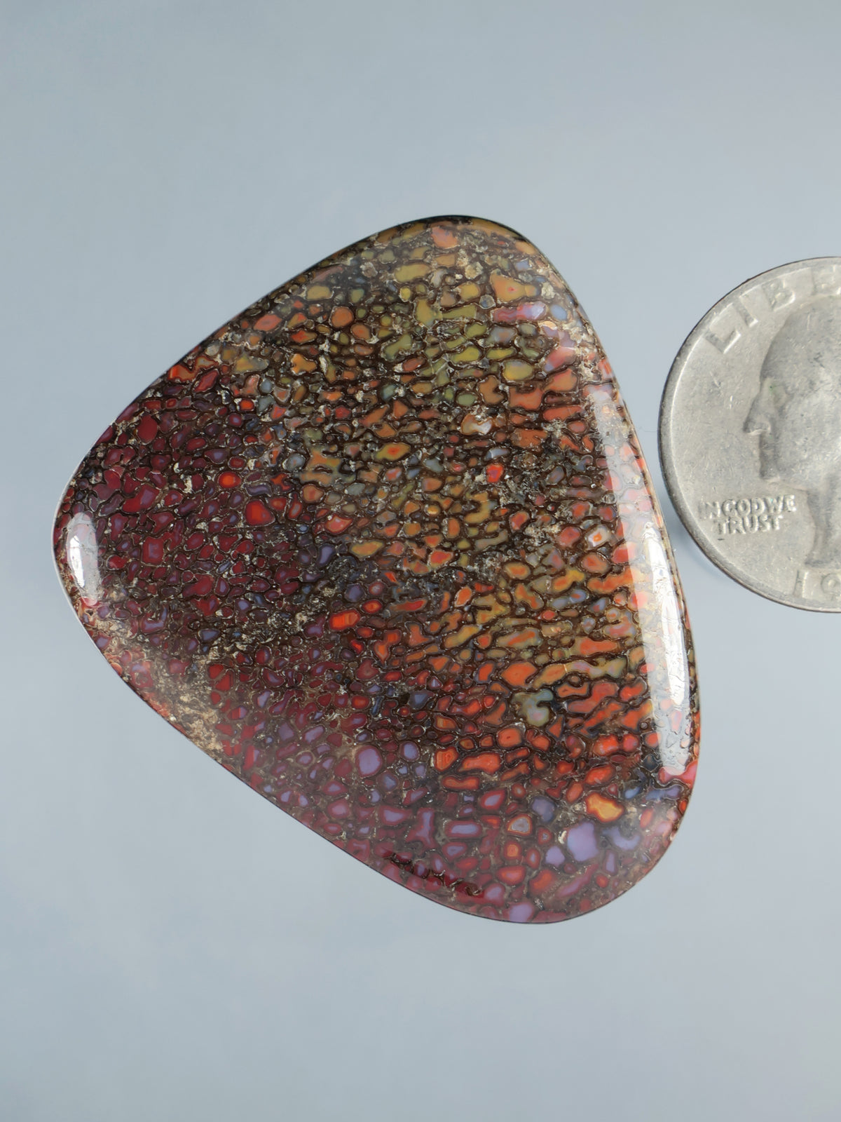 Large dinosaur gembone cabochon, rounded triangular oval with marbled red, orange and yellow speckle