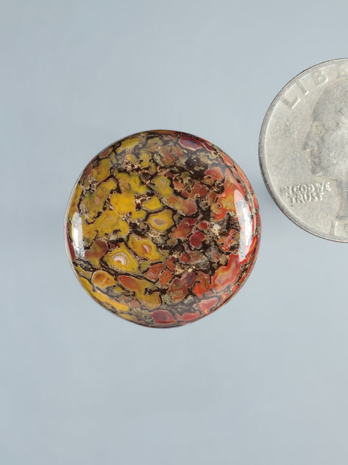 Round multicolor gembone cabochon gemstone with mottled yellow, red, and brown pattern