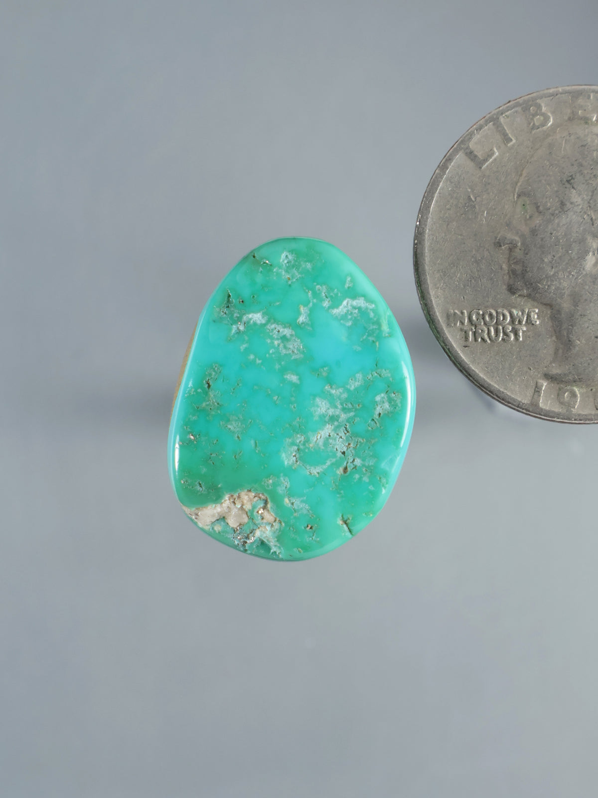 Natural Sleeping Beauty turquoise cabochon, polished oval stone with pale matrix and a coin for scale