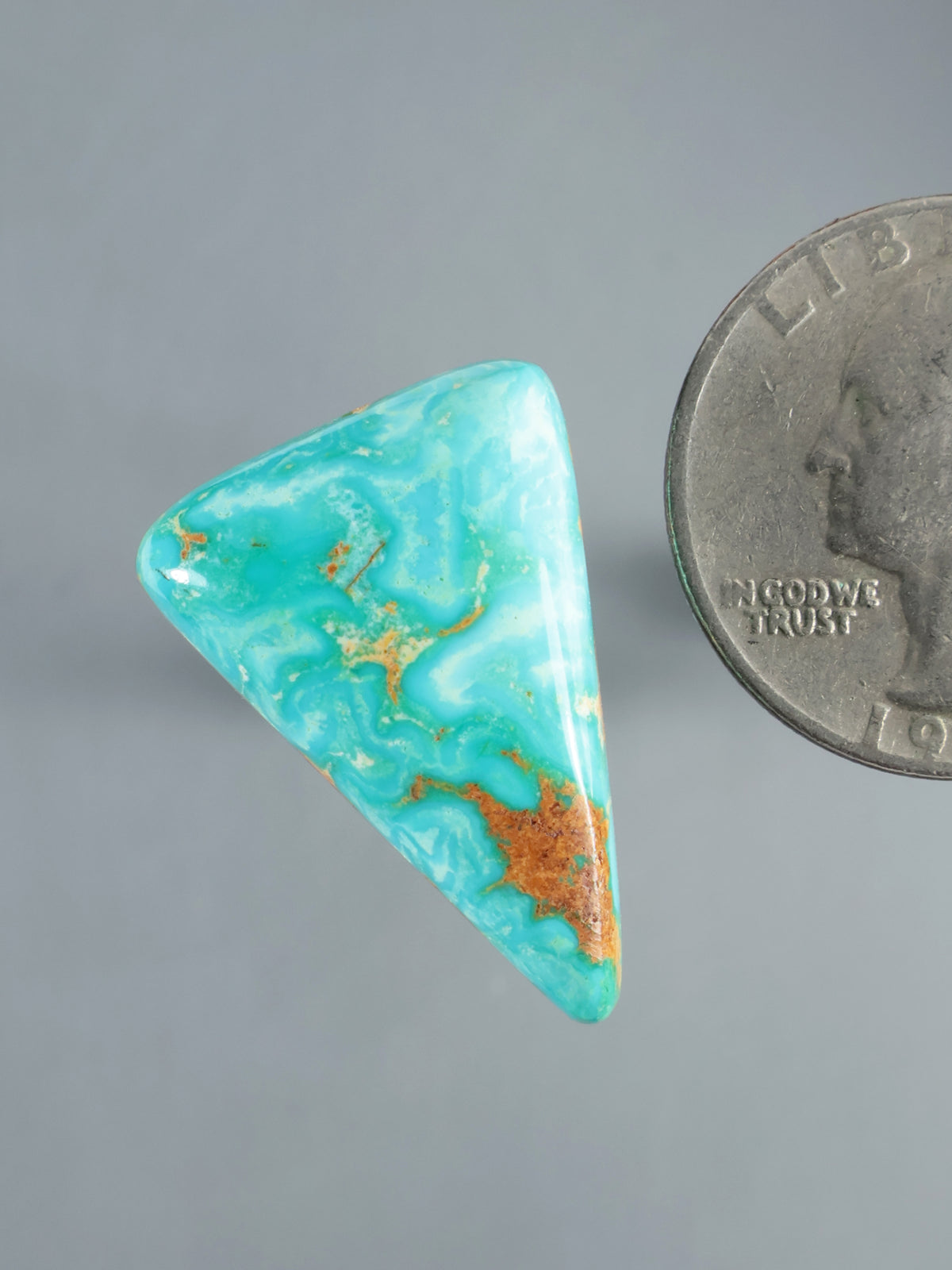 Hubei turquoise cabochon shown at an angle, with turquoise and rust-colored matrix