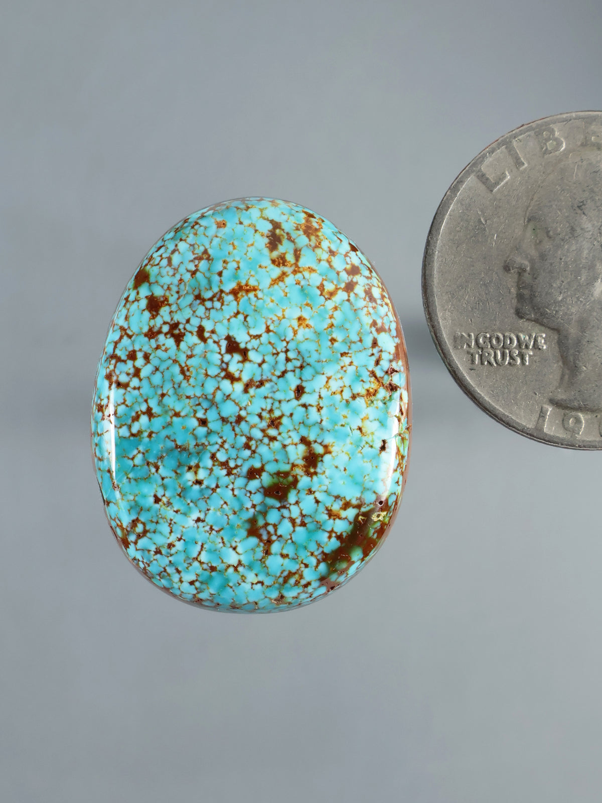 Oval turquoise cabochon with brown matrix and polished domed surface