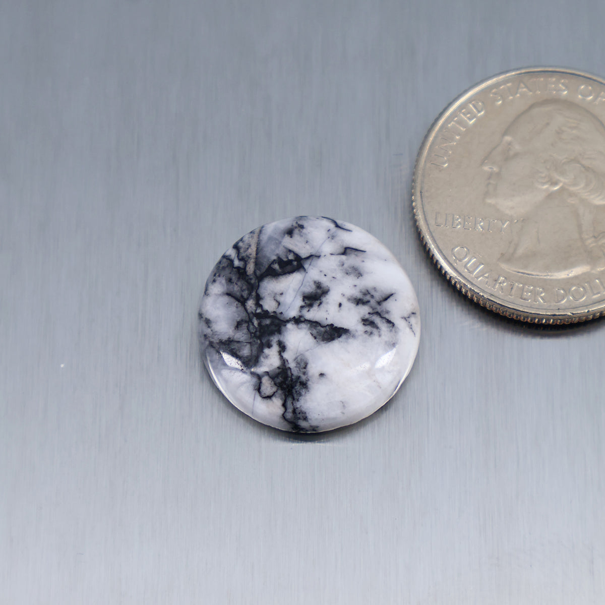 Round white feather cabochon with black marble-like veining, smooth bezel